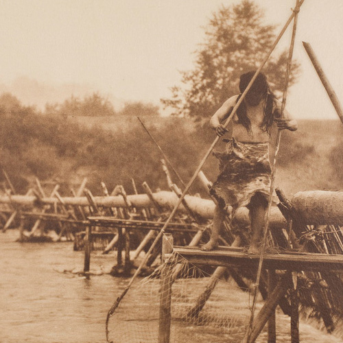 Photograph of young Native American girl standing on a fishing weir that spans a river