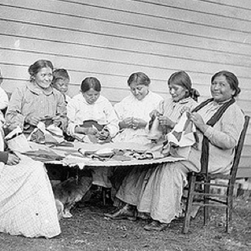 Native American women seated around a table sewing